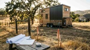 Survey stakes, blueprints, and clipboard on rustic bench marking property setback lines for a tiny house on wheels