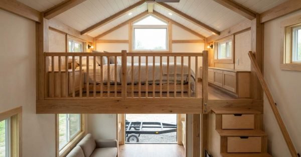 Tiny home sleeping loft with comfortable headroom, secure guardrail, storage stairs, emergency egress window, ventilation, lighting, and a clear safe escape path.